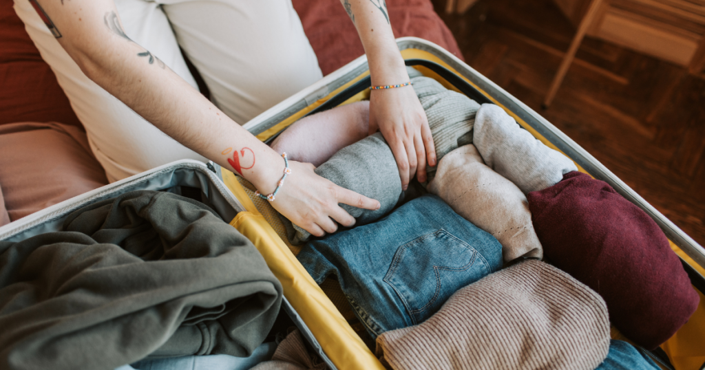 person packing suitcase with clothes