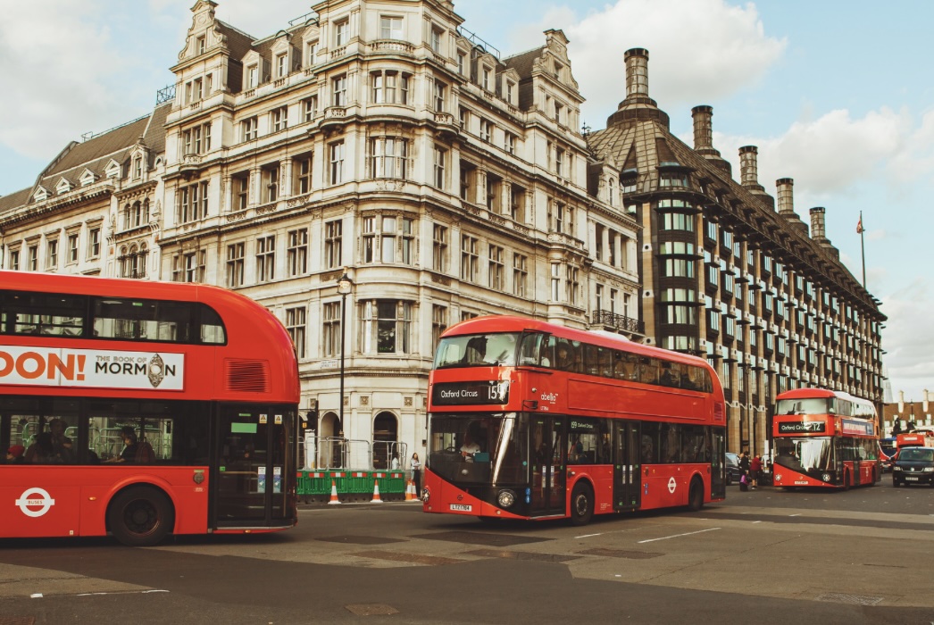 Three London red buses driving through Oxford Circus