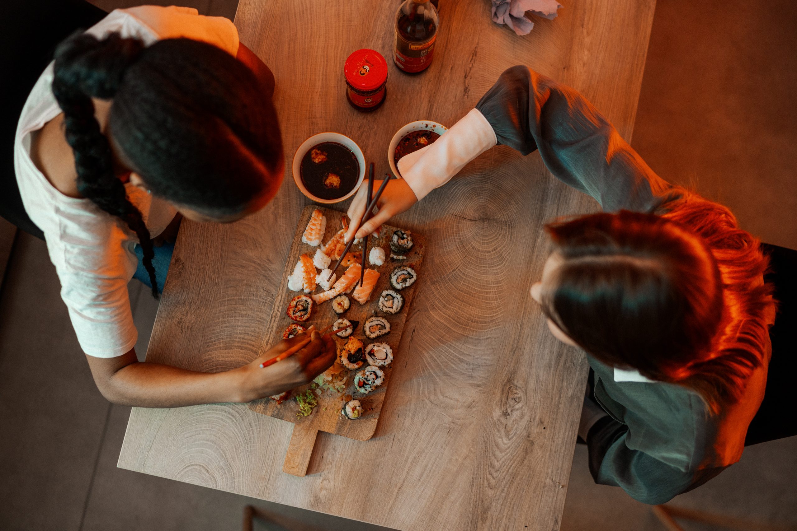 Two students eating a platter of sushi with chopsticks