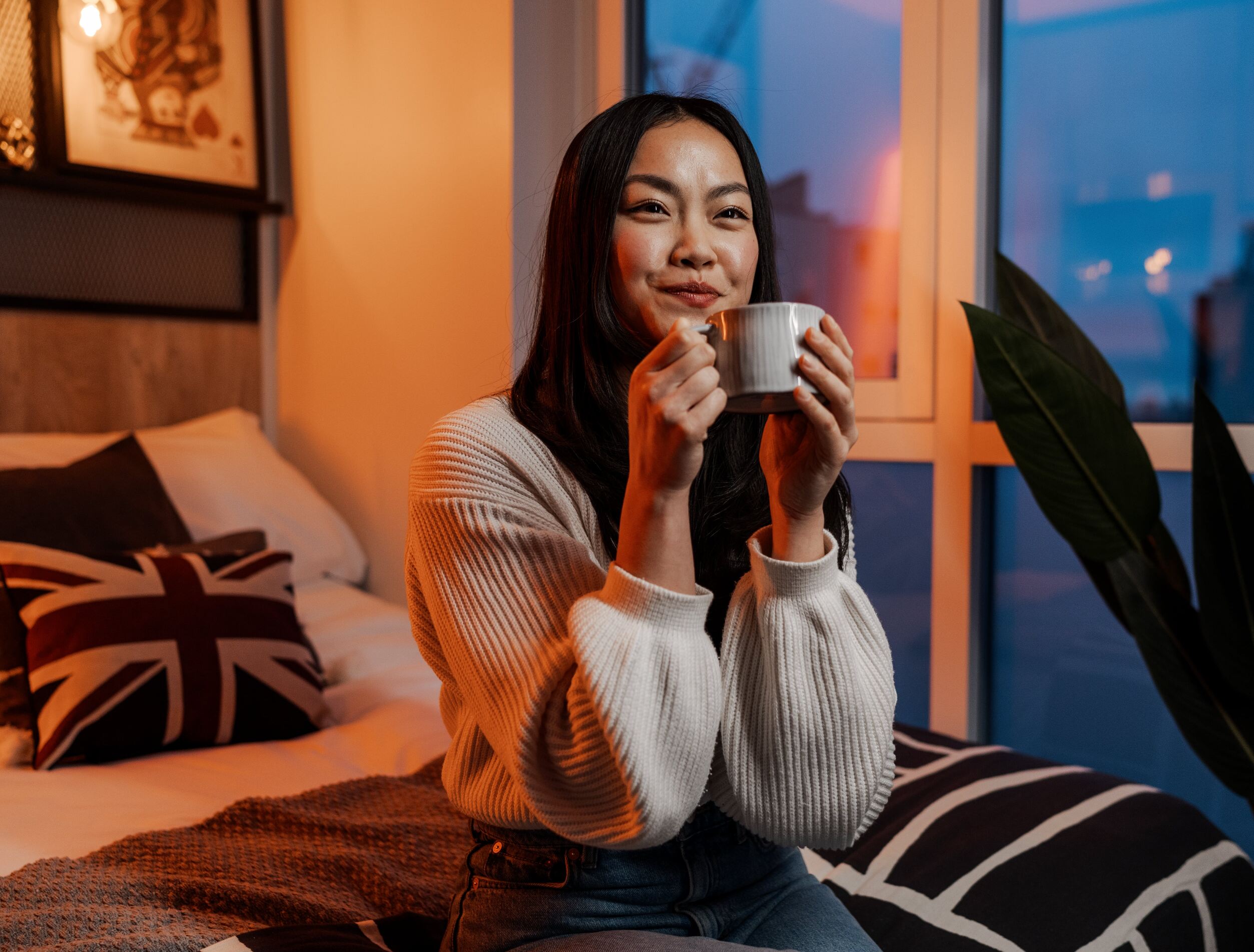 Student sat in bed with a mug in her hands