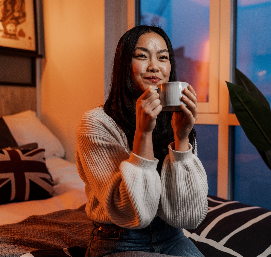 Student sat in bed holding a mug